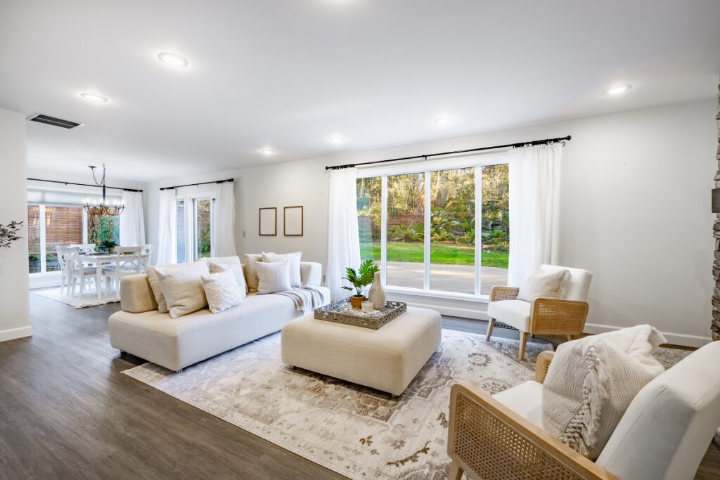 Bright, decluttered living room with natural light, neutral palette, modern lighting, and light staging